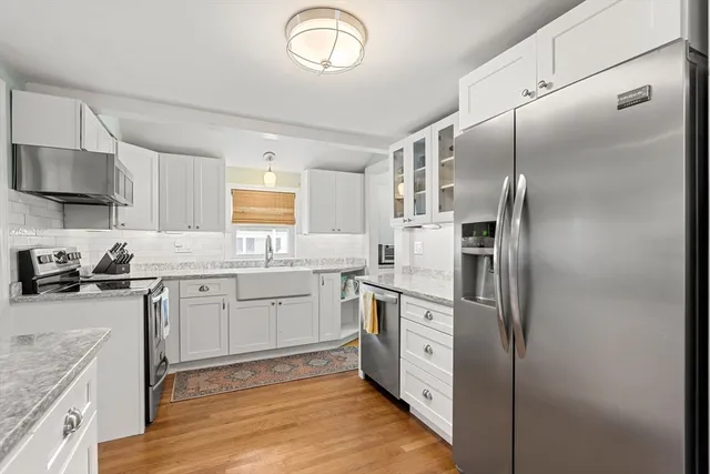 a kitchen with stainless steel appliances granite countertop a refrigerator a sink a stove and white cabinets