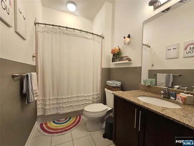 a bathroom with a granite countertop sink toilet a mirror and shower curtain