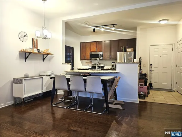 a room with stainless steel appliances kitchen island granite countertop furniture and a wooden floor