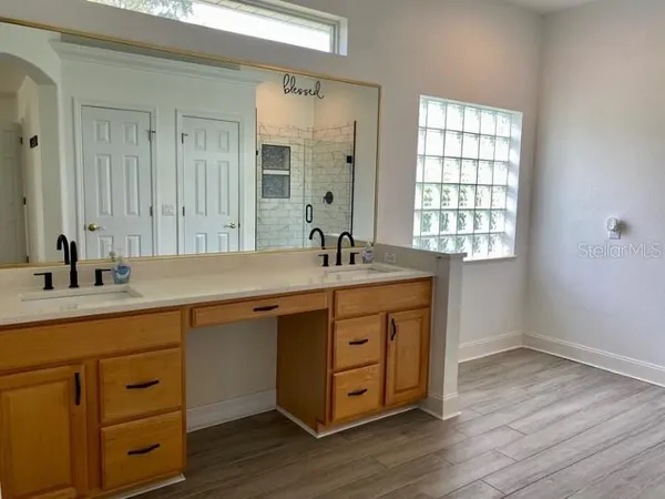 a sink with a mirror and a wooden floor
