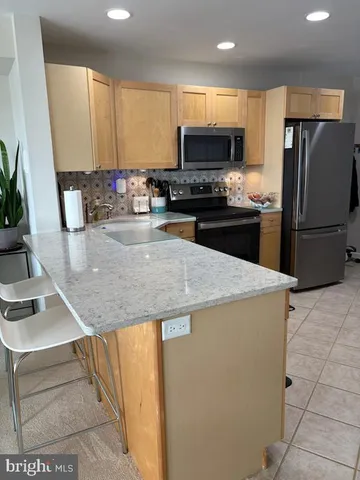 a kitchen with kitchen island granite countertop a sink a stove a refrigerator a washer and dryer