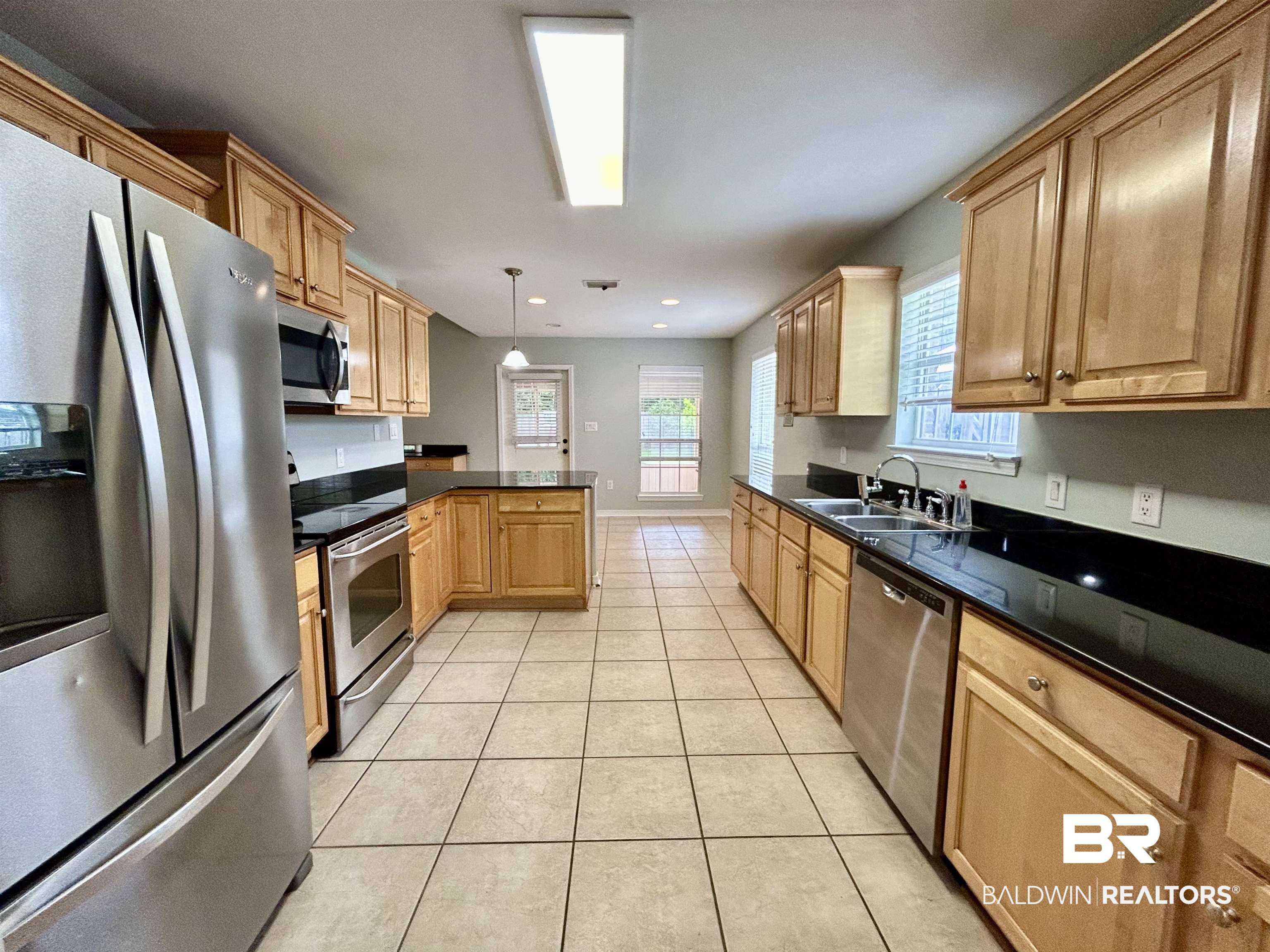 7198 Raintree Lane Gulf Shores, AL 36542 - Photo 3 of 33 Open kitchen featuring wood cabinetry and dark countertops