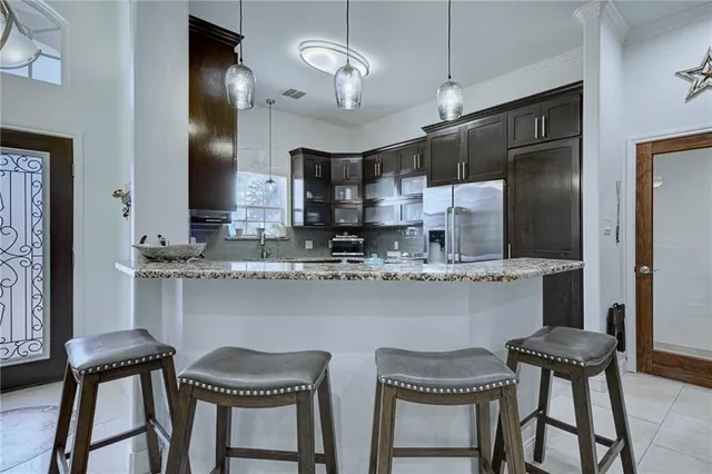 a kitchen with stainless steel appliances granite countertop a sink a stove a refrigerator and chairs