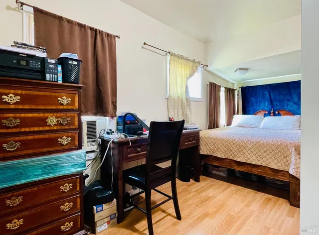 a bedroom with a bed table chair and a window