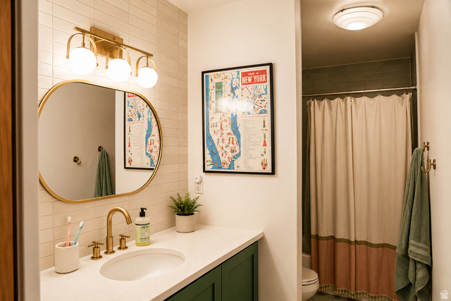 578 High Bench Road Alpine, UT 84004 - Photo 31 of 39 Bathroom featuring a white countertop with an undermount sink and brass-finish faucet, dark green cabinetry, and an oval mirror with a brass-finish frame