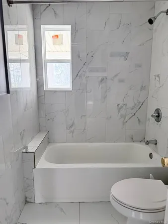 a white bath tub sitting next to a white toilet and a shower