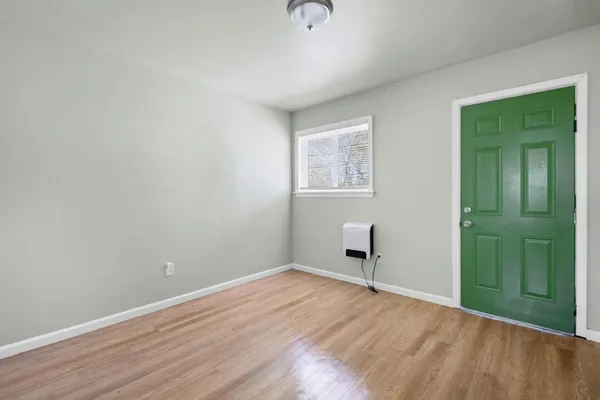 an empty room with wooden floor and a window