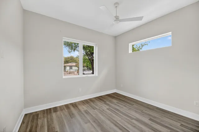 a view of an empty room with wooden floor and a window