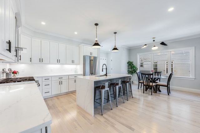 a large white kitchen with lots of counter space and dining table