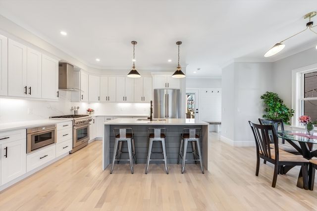 a kitchen with stainless steel appliances a table chairs sink and cabinets