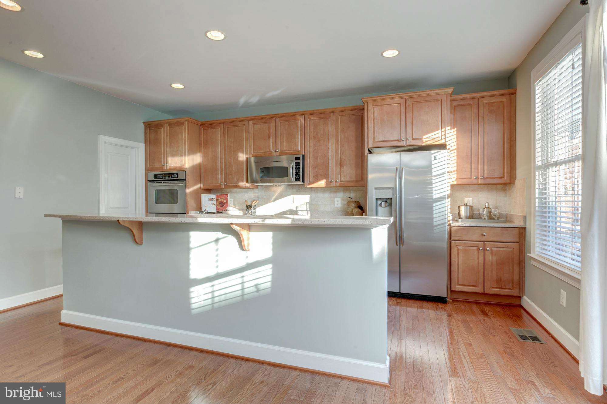 397 Spring Street Herndon, VA 20170 - Photo 10 of 30 a kitchen with kitchen island granite countertop wooden floors stainless steel appliances a sink and a window