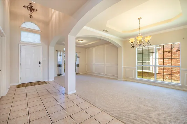 a view of an empty room with window and chandelier fan