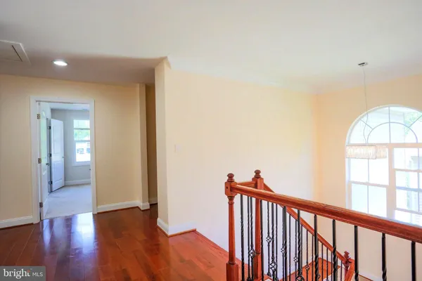 a view of a hallway with wooden floor and staircase
