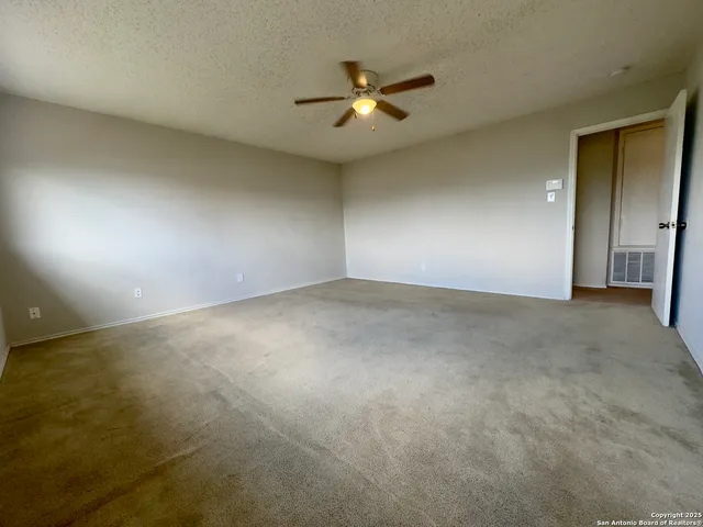 an empty room with a ceiling fan and window