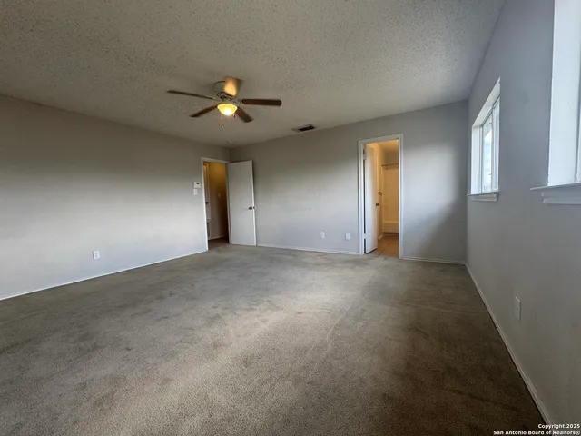 an empty room with ceiling fan and window
