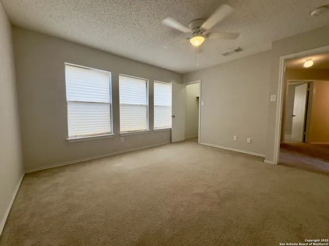 an empty room with windows and fan