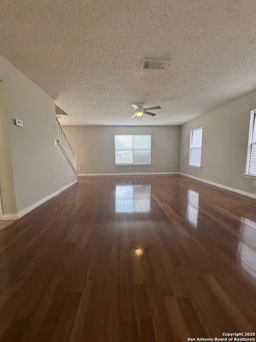 a view of empty room with wooden floor and fan