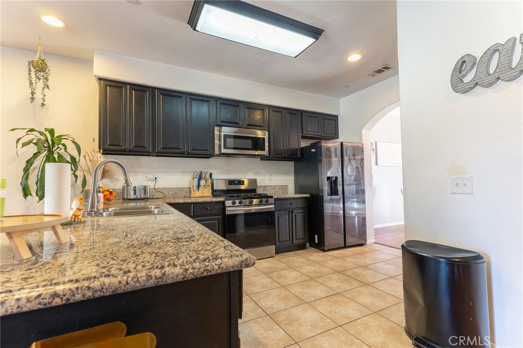 14176 Kiowa Road Apple Valley, CA 92307 - Photo 23 of 54 a kitchen with stainless steel appliances granite countertop a refrigerator a stove top oven a sink and dishwasher