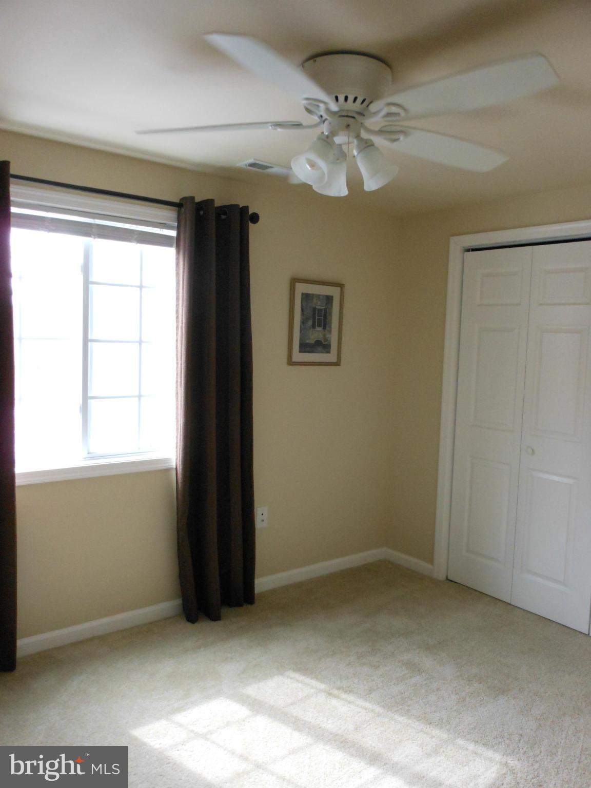 8503 Golden Ridge Court Lorton, VA 22079 - Photo 19 of 27 an empty room with a chandelier fan and windows