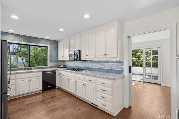 a kitchen with granite countertop white cabinets and wooden floor