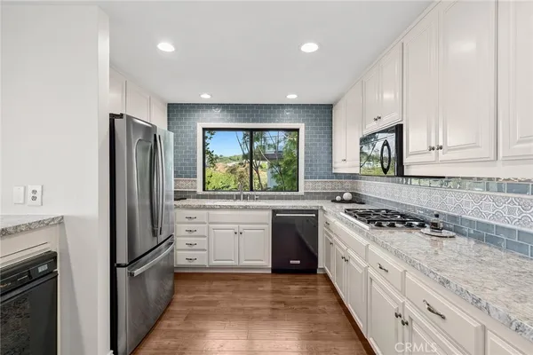 a kitchen with stainless steel appliances granite countertop a stove a sink and a refrigerator