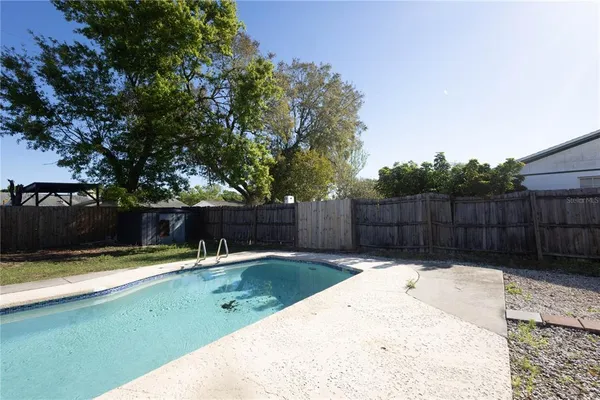 a view of a backyard with a large tree and wooden fence