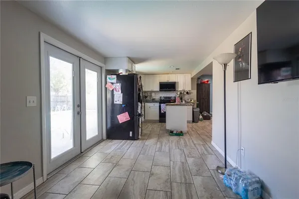 a living room with stainless steel appliances kitchen island granite countertop a refrigerator and a sink