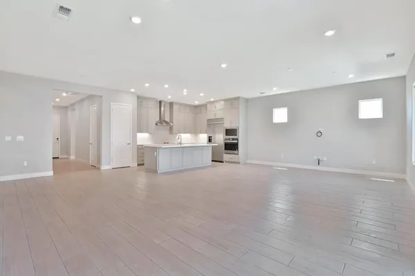 a large hall with stainless steel appliances lots of white cabinets
