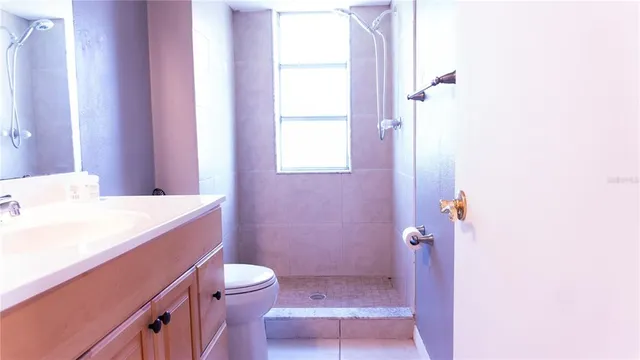 a bathroom with a sink a toilet a shower and a window