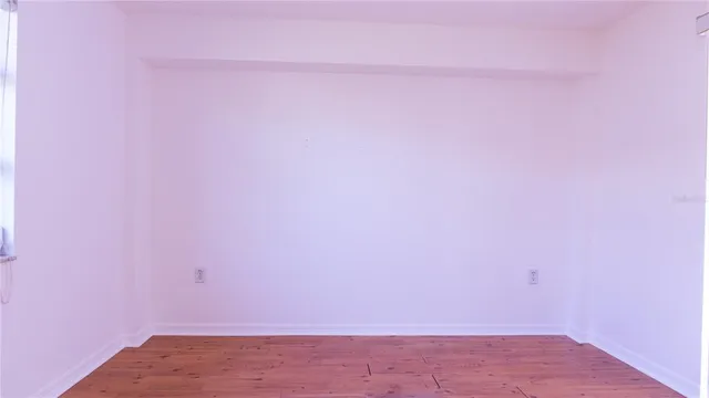 an empty room with wooden floor and closet area