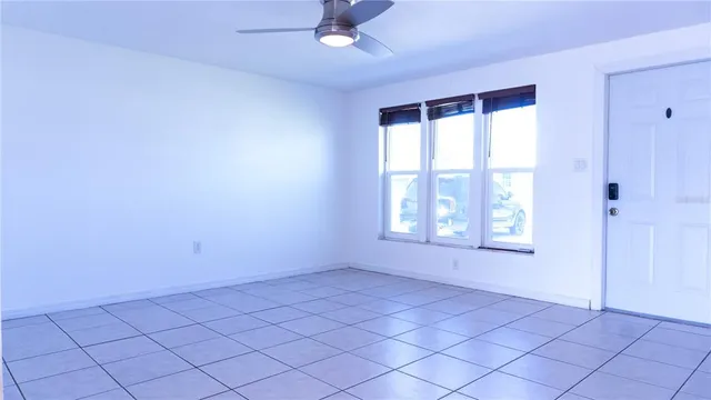 an empty room with windows and fan