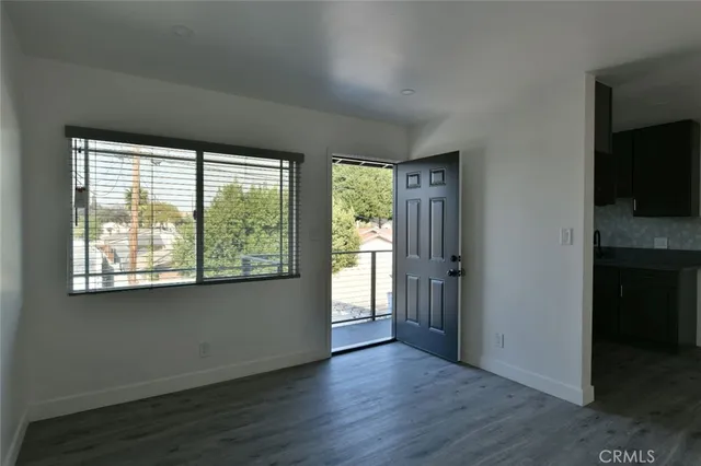 an empty room with wooden floor cabinet and windows