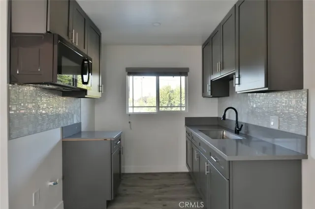 a kitchen with stainless steel appliances granite countertop a sink a microwave cabinets and a wooden floor