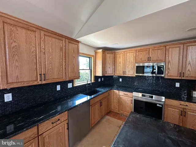 a kitchen with stainless steel appliances granite countertop a sink stove and cabinets
