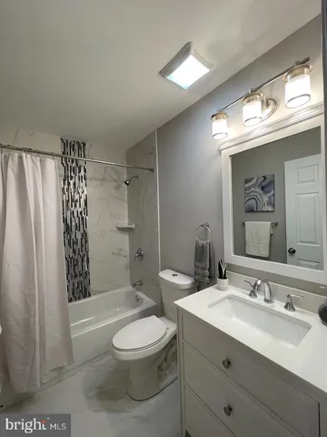 a bathroom with a toilet a sink a mirror a window and vanity