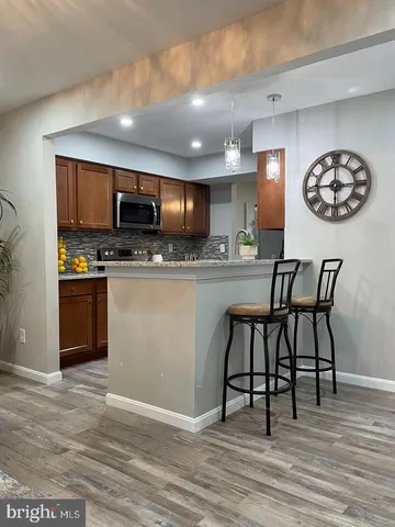 a kitchen with stainless steel appliances granite countertop a stove top oven a sink a dining table and chairs with wooden floor