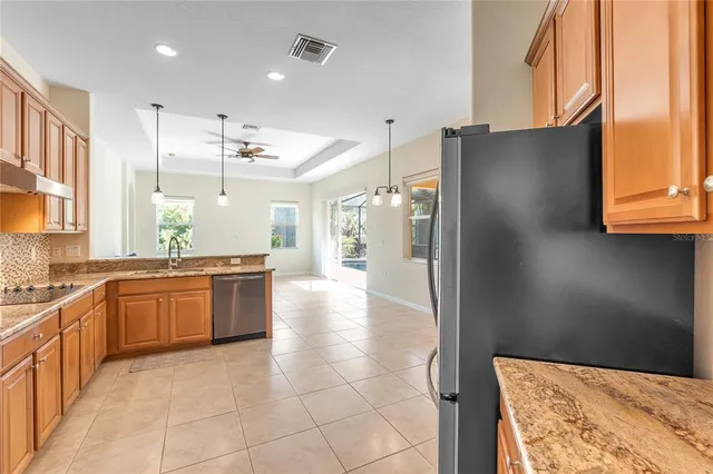 a large kitchen with stainless steel appliances kitchen island granite countertop a refrigerator and a sink