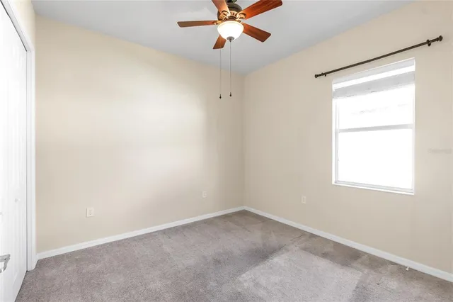 an empty room with a window and a fan