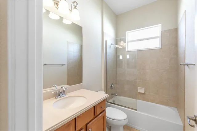 a bathroom with a granite countertop sink toilet mirror and bathtub