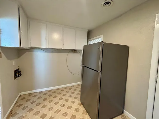 a view of a refrigerator in kitchen and an empty room