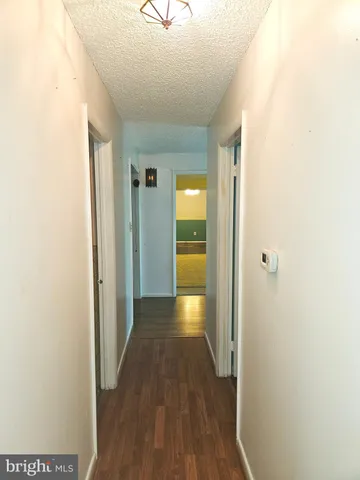 a view of a hallway with wooden floor and a refrigerator in a kitchen