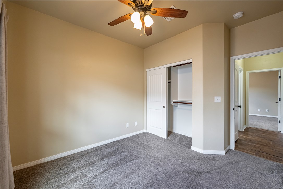 3546 North Kenneth Road Kingman, AZ 86409 - Photo 17 of 35 Room featuring warm-toned walls, gray carpeting, a ceiling fan with light fixture, and a closet with a white bi-fold door