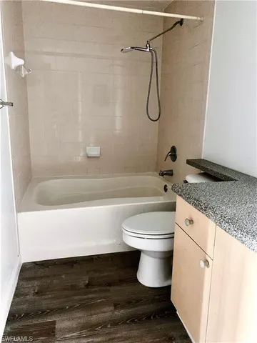 a bathroom with a granite countertop bathtub shower sink and toilet