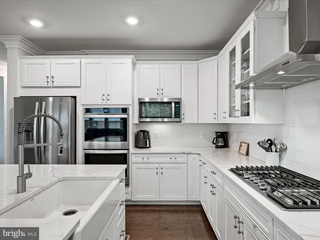a large kitchen with kitchen island a large counter space a sink a stove and white cabinets