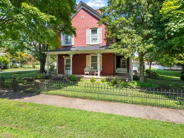 a view of a house with a big yard plants and large trees
