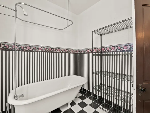 a view of an empty room with window and chandelier fan