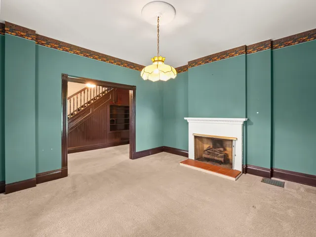 an empty room with fireplace cabinet and windows