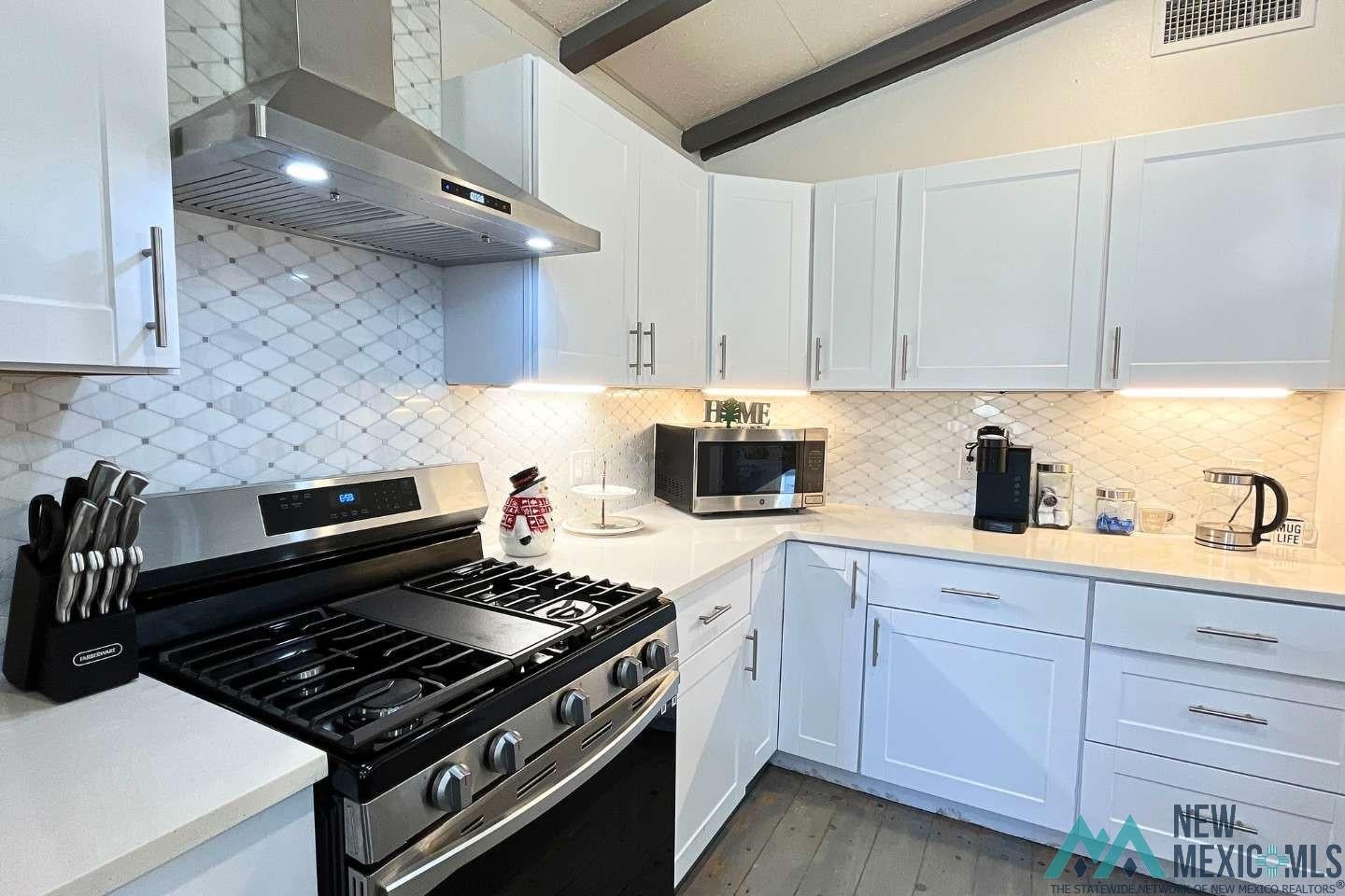 241 Junction Road Ruidoso, NM 88345 - Photo 6 of 44 Kitchen featuring stainless steel appliances, wall chimney exhaust hood, white cabinetry, and backsplash