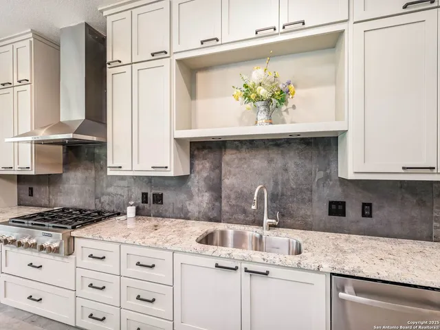a kitchen with granite countertop a sink stove and cabinets