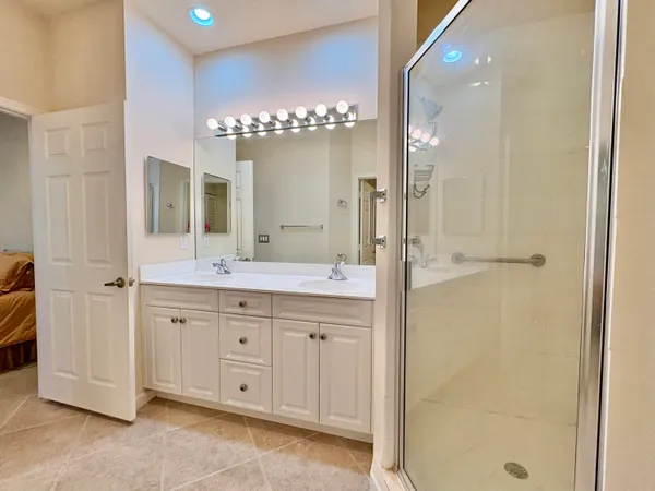 a spacious bathroom with a double vanity sink a large mirror and shower